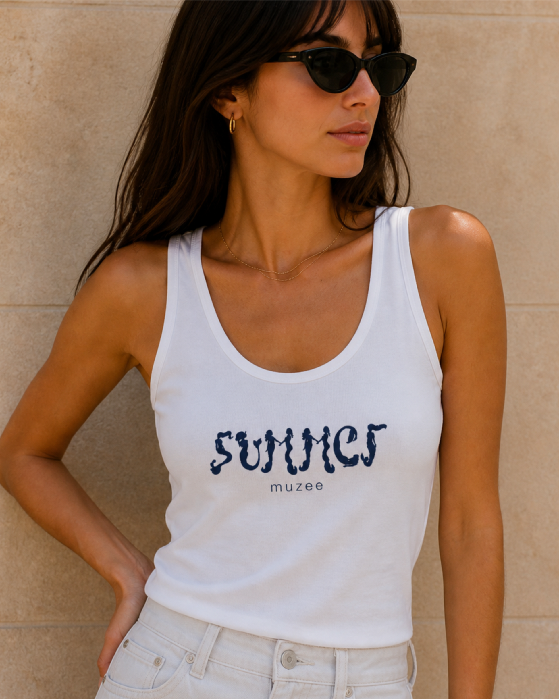 White organic cotton mermaid tank top by Muzee, worn by woman leaning against a warm beige wall